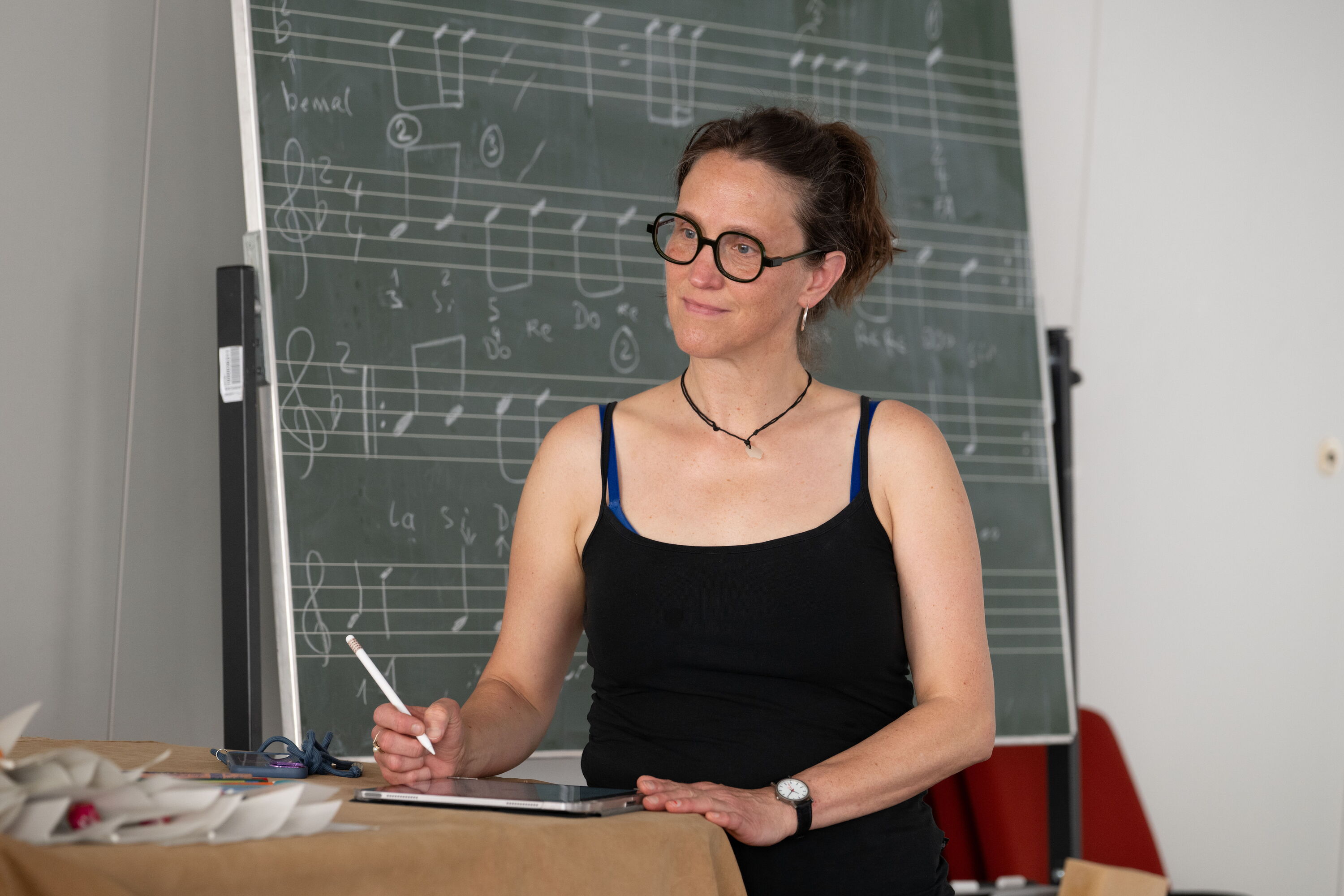 Frau mit Tablet vor Notentafel in einem Seminarraum